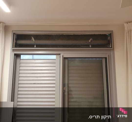 תריסים מתכתיים סגורים על חלון זכוכית גדול